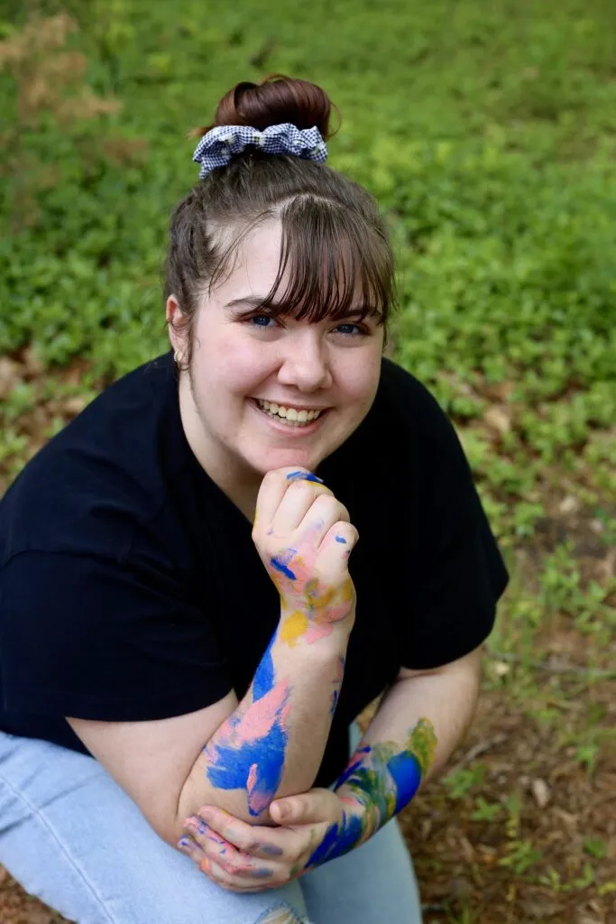 Portrait of artist Kylie Sharee, paint on her arm, outdoors